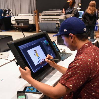 2017 Studio, attendee draws SIGGRAPH mascot Shay D. Pixel at t-shirt printing station